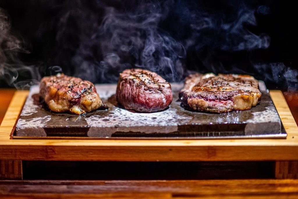 Trio of steaks sizzling on hot stone