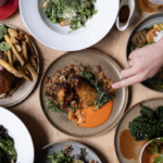 Lots of small plates with hands reaching for food