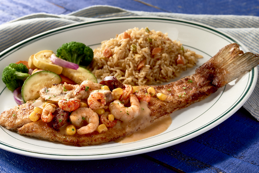Cooked fish on plate with prawns, veg and rice